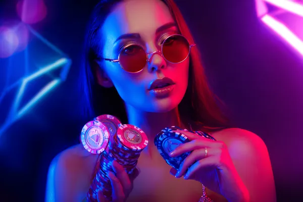 নিয়ন আলোয় আলোকিত পরিবেশে ক্যাসিনো চিপ হাতে এক অভিজাত নারী—যা 456BDD–এর প্রিমিয়াম অনলাইন ক্যাসিনো পরিবেশকে তুলে ধরে।