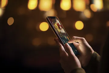 A woman smiling by bright slot machines showing lucky symbols, showcasing the exciting slot offerings at 456BDD.